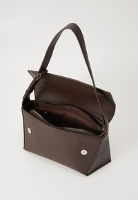 Sac à main en cuir marron avec un design structuré, doté d'un rabat supérieur, d'une poche zippée et de fermetures à pression en argent. Bandoulière réglable incluse.