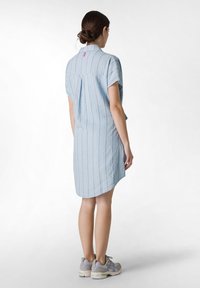 Light blue short-sleeve dress with vertical stripes, a buttoned collar, and a pleat at the back, paired with gray athletic shoes.