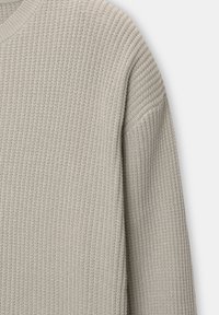 Hellgrauer gestrickter Pullover mit geripptem Muster, versehen mit einem Rundhalsausschnitt und abgesenkten Schulternähten für eine entspannte Passform.