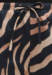 Λάστιχο με κορδόνι και μοτίβο ζέβρας σε μαύρο και μπεζ σε ελαφριά παντελόνια από ύφασμα.