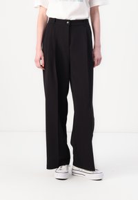 Black wide-leg trousers with a high waist, featuring a single button closure and belt loops. Smooth fabric, paired with white sneakers.