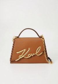Hnědá kožená kabelka s pevnou strukturou, zdobená zlatým řetízkem a charakteristickou ozdobou „Karl“ v kurzívním stylu.