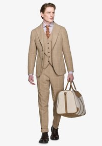 Lysbrun tre-delt jakkesæt med et ternet mønster. Kombineret med en stribet skjorte og et brunt prikket slips. Holder en beige og brun taske.