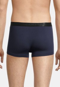 Navy blue boxer briefs with a black elastic waistband featuring logo text. Material is smooth and form-fitting, with a mid-thigh cut.