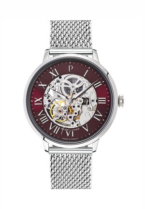 Montre au ton argenté avec un cadran bourgogne, présentant un design squelettique. Des chiffres romains marquent les heures. Bracelet en maille métallique. Fabriqué en France.
