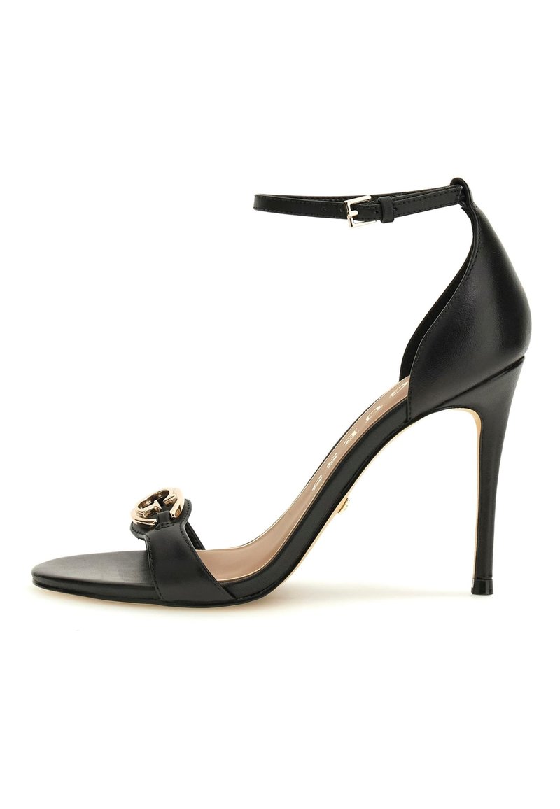 Schwarze High-Heel Sandale mit Knöchelriemen, offener Zehenpartie und goldener dekorativer Schnalle am vorderen Riemen.