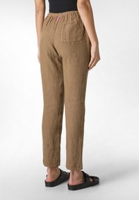 Bruna linbyxor med avslappnad passform, med elastisk midja, bakficka och beskuren längd. Bärs med svarta skor.