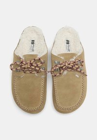 Bež semiš natikači z belo podlogo iz flisa in rdeče vzorčenimi vezalkami, šivanimi detajli in kovinskimi luknjicami.