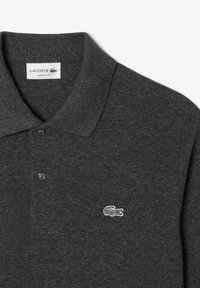 Polo shirt grigio scuro con taglio classico, colletto corto, due bottoni neri e un piccolo logo di coccodrillo ricamato in bianco sul petto.