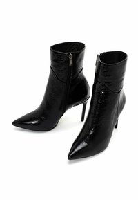Schwarze Knöchelstiefel mit spitzer Zehenpartie, aus glänzendem, strukturiertem Material; ausgestattet mit einem seitlichen Reißverschluss und schlanken, hohen Absätzen.