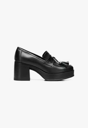 Schwarze Leder-Plateau-Loafer mit runder Zehenpartie, verlängertem Schaft und quergestepptem Akzent. Besitzt einen Blockabsatz mit vertikalen Rillen.