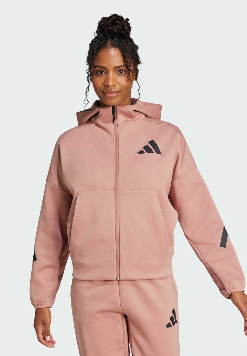 Sudadera con cremallera rosa con capucha, que presenta una tela texturizada, bolsillo delantero y acentos de logo negro en el pecho y las mangas.
