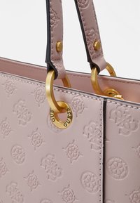 Sac à main en cuir synthétique rose avec un motif de logo embossé, quincaillerie en ton doré et détails noirs sur les poignées. Caractérisé par un détail en forme d'anneau en métal rond.
