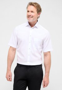 Witte korte mouwen shirt met een button-down kraag, een borstzak, zwarte knopen en een subtiel patroon aan de binnenkant van de kraag. Draag het met zwarte broek.
