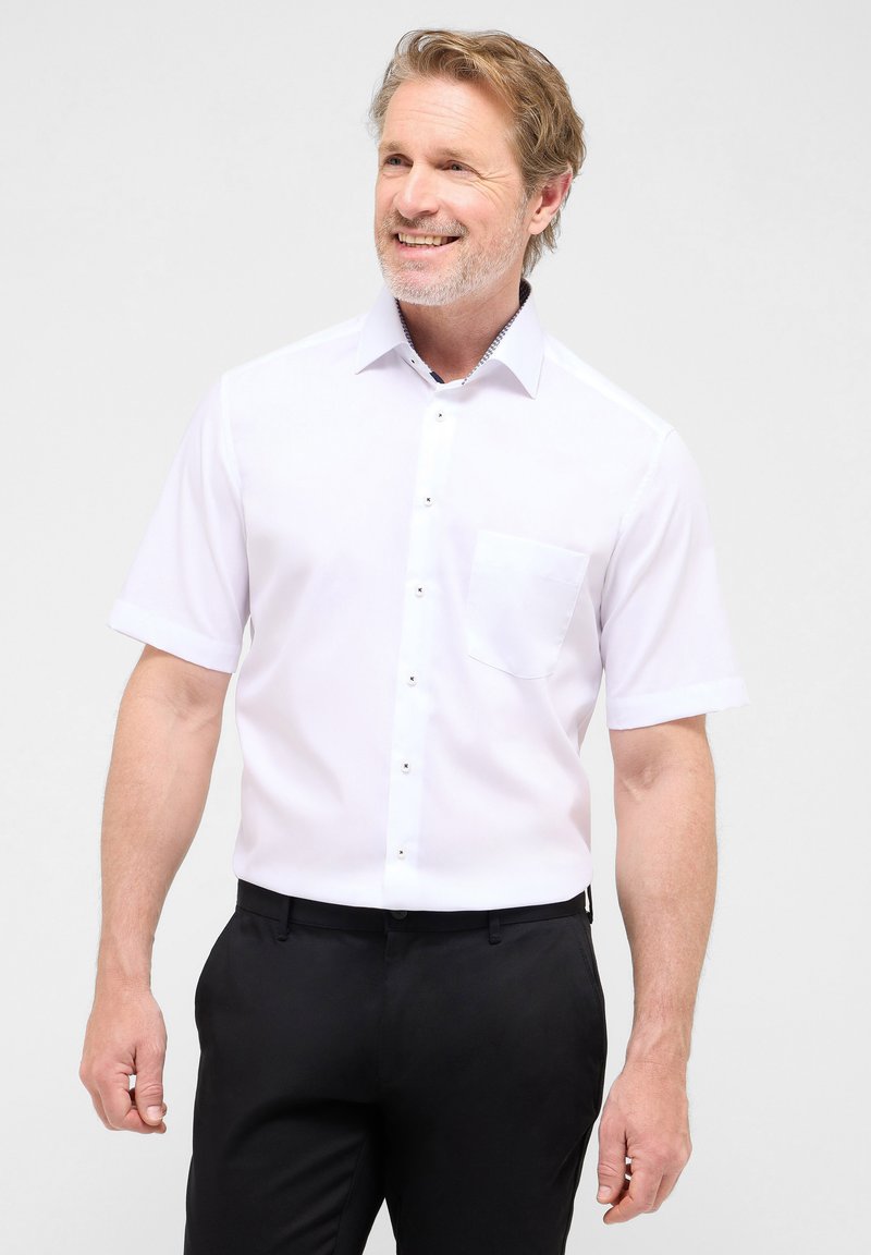 Witte korte mouwen shirt met een button-down kraag, een borstzak, zwarte knopen en een subtiel patroon aan de binnenkant van de kraag. Draag het met zwarte broek.