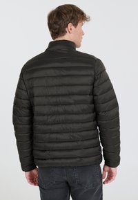 Svart puffjacka med horisontell quiltning, hög krage och elastiska manschetter. Slät tygtextur med en åtsittande design.