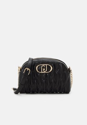 Zwarte gewatteerde lederen crossbodytas met gouden kettingriem, verstelbare gesp en een gouden ovale logo-plaat aan de voorkant.