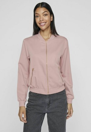 Roze bomberjack met een ritssluiting aan de voorkant, geribbelde manchetten en zakken, gemaakt van gladde stof met een getailleerde taille. Gekoombineerd met donkere jeans.
