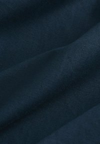 Tissu bleu foncé avec une texture douce, légèrement froissée et un fin motif de tissage visible.