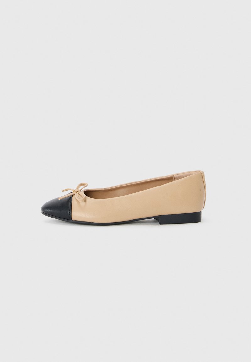 Beige ballerinat taiat din piele cu vârful negru, având un mic detaliu în formă de fundiță în față și un toc mic din cauciuc negru.