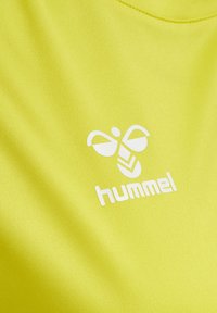 Neon gul atletik skjorte med et hvidt logo med et stiliseret bi-design og mærkenavnet "hummel" nedenfor. Glat, let materiale.