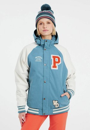 Blauwe en witte jas met een capuchon, voorzien van een oranje letter 'P' en een badge. Textuurstof en gestreepte manchetten. Gecombineerd met een gestreepte muts.