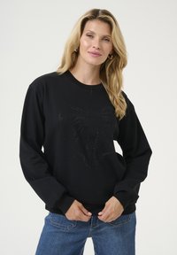 Zwart sweatshirt met lange mouwen, met een textuur van een strikdesign gemaakt van rhinestones op de voorkant. Relaxte pasvorm, ronde halslijn.