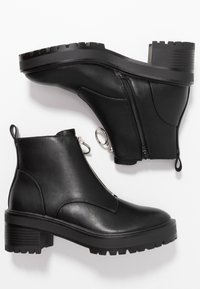 Black leather ankle boots with side zip closure, textured rubber sole, and loop pull tabs. Features a rugged tread design for grip.