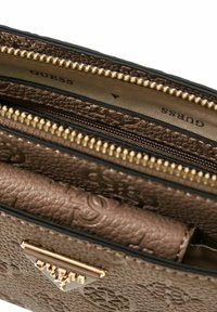 Bruine leren portemonnee met textuur, gouden accenten, meerdere vakken en een reliëfpatroon. Logo zichtbaar binnenlangs de ritsranden.