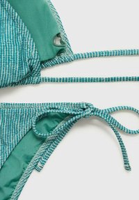 Turkizni bikini zgornji in spodnji del z teksturiranim, šahovskim vzorcem. Prilagodljive vezalke na straneh in trakovi. Gladka tkanina z mehkim zaključkom.