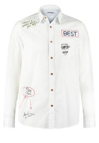 Vit långärmad skjorta med träknappar, prydd med broderade detaljer: "BÄST," en ansiktsillustration och handskrivna anteckningar i grönt och rött.