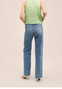 Haut sans manches vert clair avec un motif géométrique, associé à un jean denim bleu clair à jambes droites, avec poches arrière et texture délavée.
