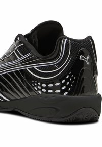 Scarpa sportiva nera con pannelli lucidi, mesh testurizzato e accenti bianchi. Presenta un tacco arrotondato e dettagli perforati per la traspirabilità.
