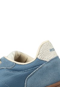 Blå tygsko med en texturerad beige läderklack, rund tå och mjukt foder. Har ljusa sömmar och en brun gummisula.