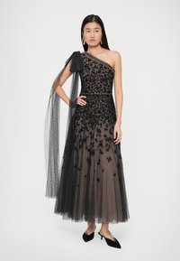 Rochie de seară din tul negru, cu broderie florală, design cu un umăr și detaliu de fundă translucidă. Lungime până la podea, cu fustă în straturi.
