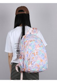 Zaino multicolore con un motivo maculato in rosa, arancione, blu e verde, dotato di diversi scomparti con zipper e spallacci imbottiti.