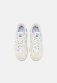 Białe sneakersy z teksturowaną skórą i siateczkowym wierzchem, okrągłym noskiem, sznurowanym przodem oraz jasnoniebieskim logo na języku i boku.
