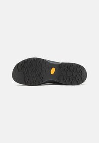 Schwarze Gummisohle mit strukturiertem Muster, ausgestattet mit einem Vibram-Logo. Oberer Teil nicht sichtbar. Ausgelegt für Traktion und Langlebigkeit.