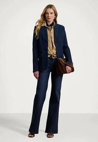 Σκούρο τζιν σακάκι πάνω από μια ανοιχτόχρωμη πουκάμισο με κουμπιά, συνδυασμένο με φαρδιά σκούρα τζιν, καφέ ζώνη και καφέ τσάντα. Λείες υφές και καθαρές γραμμές.