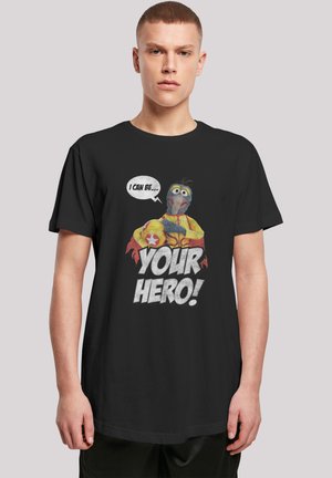Black t-shirt featuring a colorful graphic of a puppet character with speech bubble reading "I CAN BE... YOUR HERO!" in bold text.