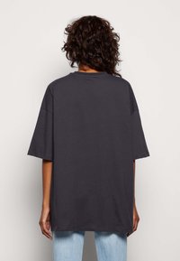 T-shirt oversized grigio scuro con scollo rotondo, maniche corte e vestibilità ampia, realizzato in morbido cotone. Semplice, senza motivi.