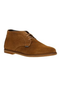 Stivali chukka in camoscio marrone con punta rotonda, design minimalista con lacci e suola in gomma semplice. Presenta dettagli cuciti e un'etichetta di branding.