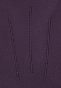 Lila Leder mit einer strukturierten Oberfläche, das drei vertikale genähte Linien aufweist. Die Nähte heben sich leicht von der Lederoberfläche ab.