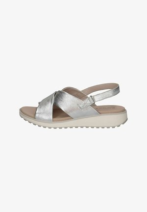 Strieborné kovové sandále s krížovými popruhmi, nastaviteľným popruhom okolo členka a svetlo béžovou platformou. Hladká textúra a priedušný dizajn.