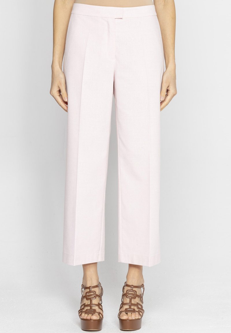 Jasnoróżowe, dopasowane spodnie z szerokimi nogawkami, z fałdami, gładką fakturą i wykończeniem bez zbędnych detalów, zestawione z brązowymi sandałami na platformie z paskami.