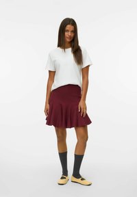Weißes T-Shirt mit kurzen Ärmeln, kastanienbrauner schwingender Rock, graue knielange Socken und gelbe Schuhe mit schwarzen Akzenten. Einfaches und modernes Design.