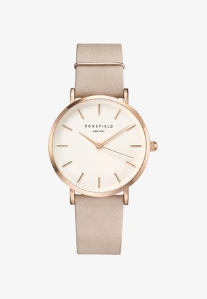 Montre ronde avec un bracelet en cuir suédé beige, un boîtier en or rose, un cadran blanc, des index horaires simples et deux aiguilles fines. Logo de la marque visible.