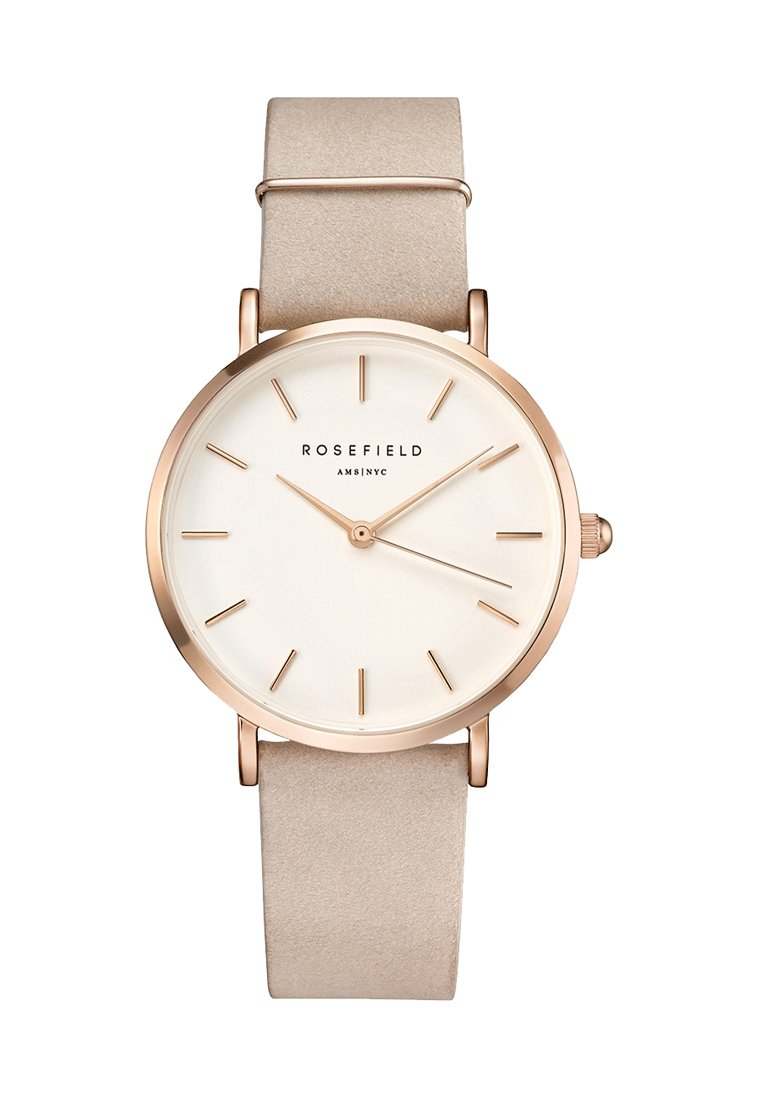 Montre ronde avec un bracelet en cuir suédé beige, un boîtier en or rose, un cadran blanc, des index horaires simples et deux aiguilles fines. Logo de la marque visible.