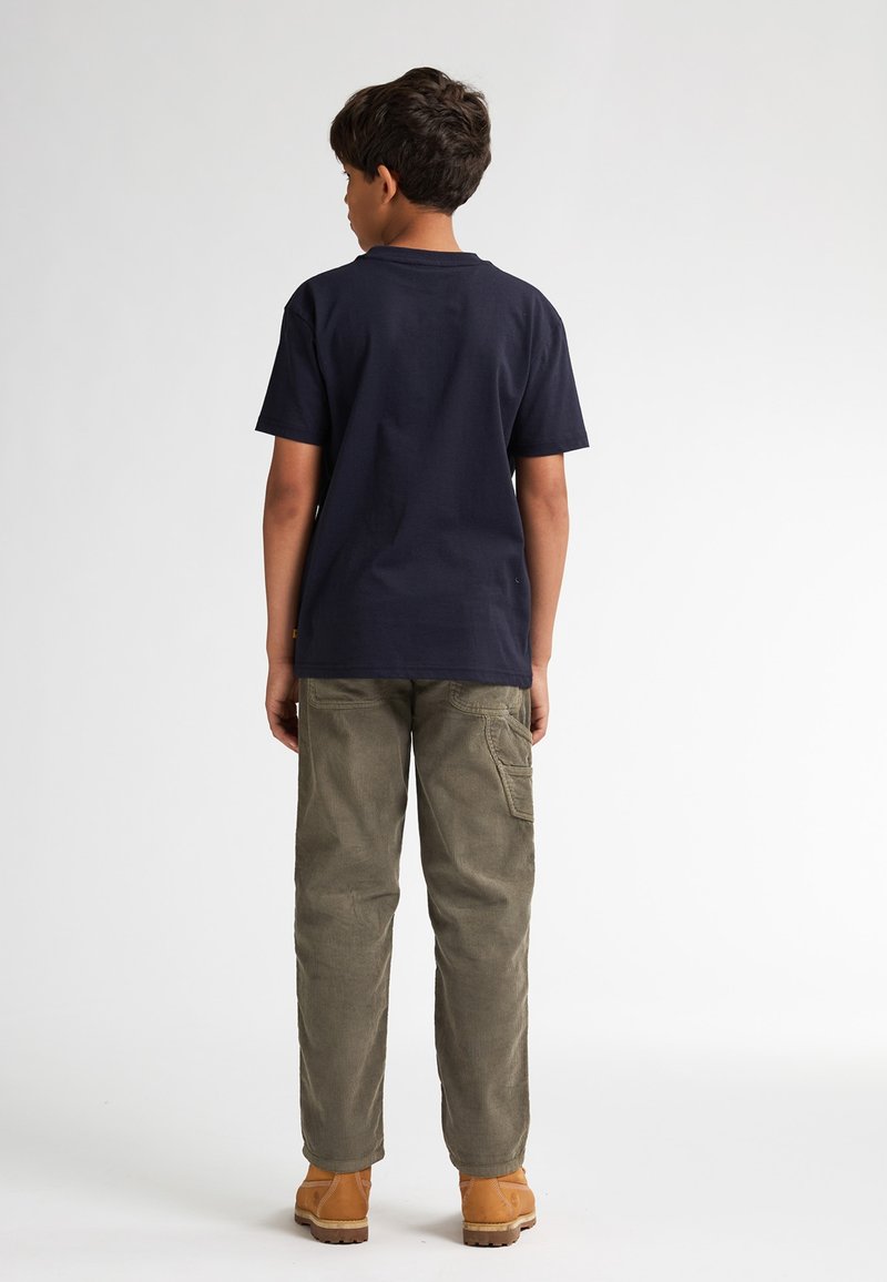 Marineblauw katoenen t-shirt gecombineerd met olijfgroene cargobroek. De outfit heeft een losse pasvorm en praktische zakken. Bruine schoenen maken de look compleet.