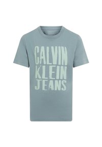 Camiseta de algodón azul claro con gran texto en negrita de color verde claro "CALVIN KLEIN JEANS" en la parte frontal. Cuello redondo clásico y mangas cortas.
